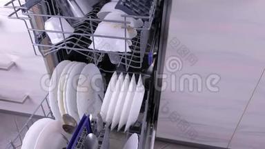 洗碗机篮子，厨房里有脏的白色盘子和餐具。